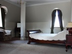 pokój w dworze Sieraków, łóżko brązowe z białą pościelą