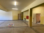 Sala lekcyjna w trakcie modernizacji.Ściany pomieszczenia są żółte. Na ścianie wisi czerwona duża skrzynka